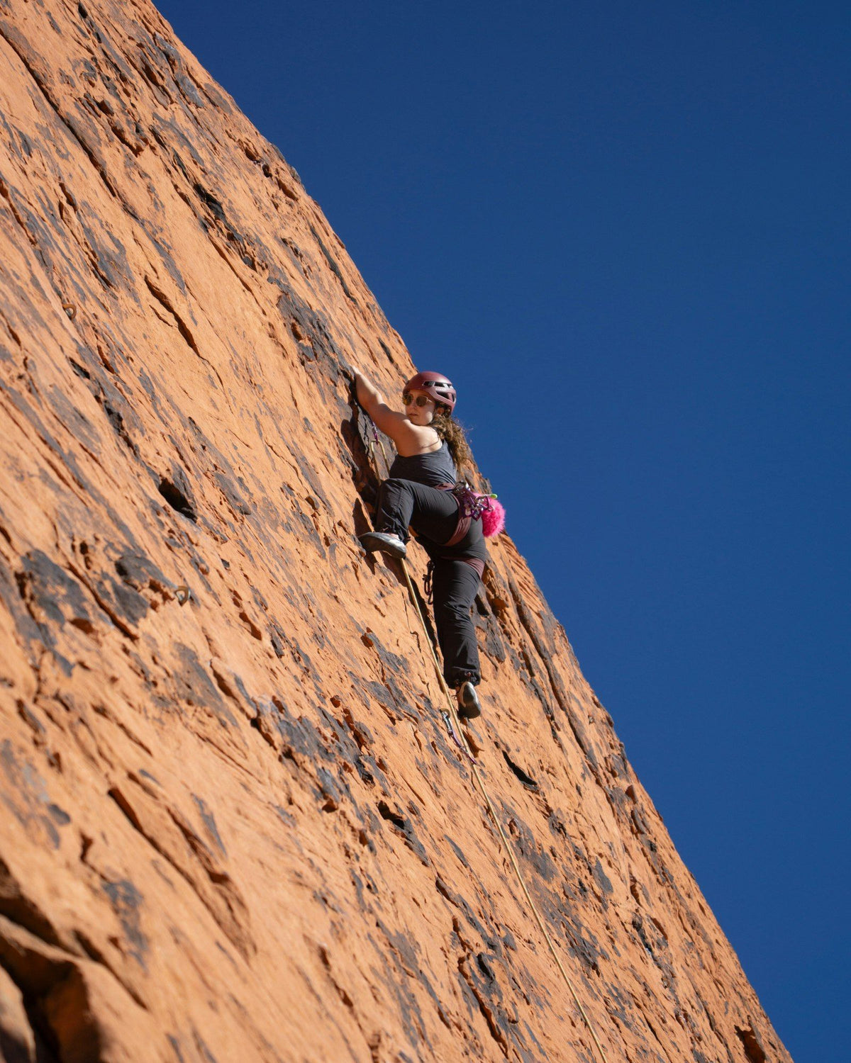 A woman rock climbing a steep sandstone wall